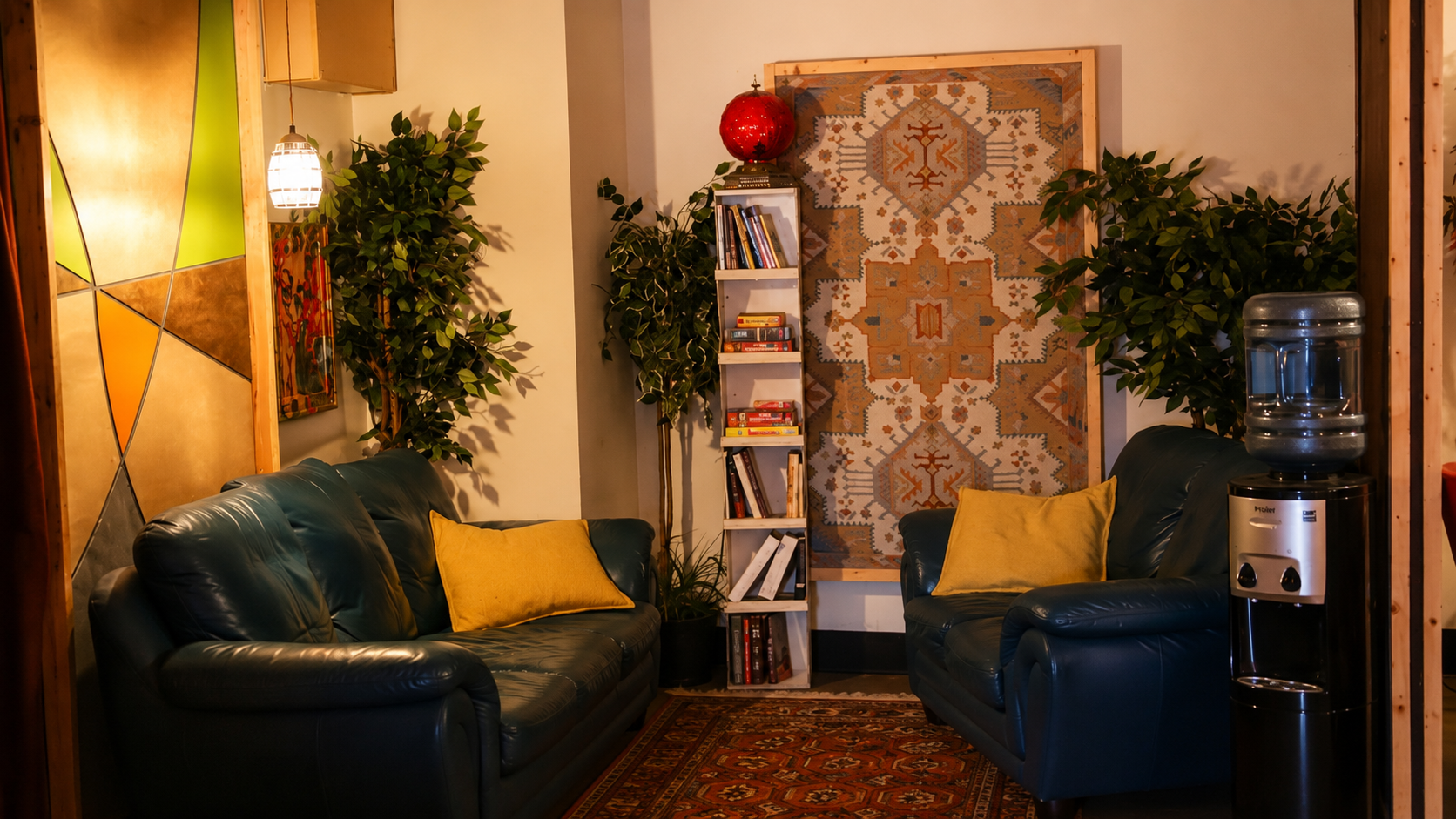 Cozy reading nook with teal leather sofas, a full bookshelf, and hanging tapestry